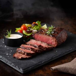 A dry-aged Wagyu ribeye steak served with fresh salad and tofu mayo, showing rich marbling and a premium fine dining presentation.